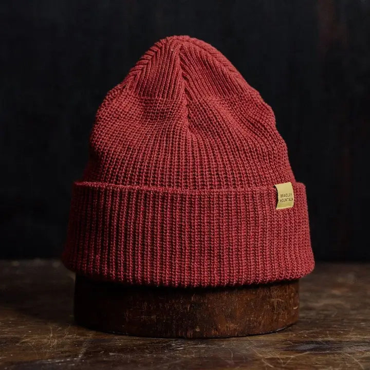 Rich brick-red knit beanie with a folded brim, blending cozy warmth with a bold, rugged look