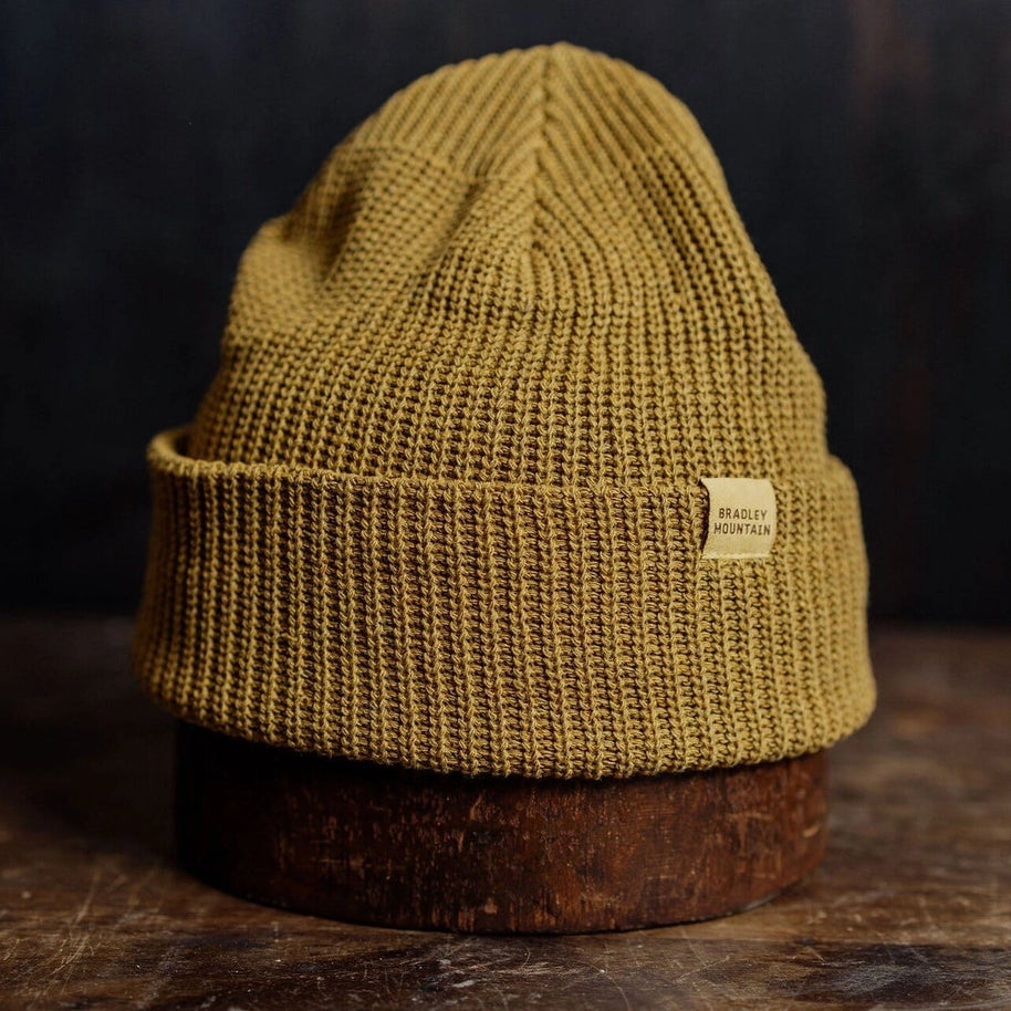 Cozy mustard knit beanie with a folded brim and rugged style, offering warmth and a timeless outdoors look