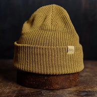 Cozy mustard knit beanie with a folded brim and rugged style, offering warmth and a timeless outdoors look