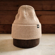 Neutral sand-colored knit beanie with a folded brim, offering cozy warmth and minimalist outdoor style