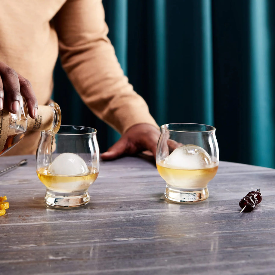 Stylish whiskey glasses with round ice spheres, shown in use for a refined sipping and cocktail experience