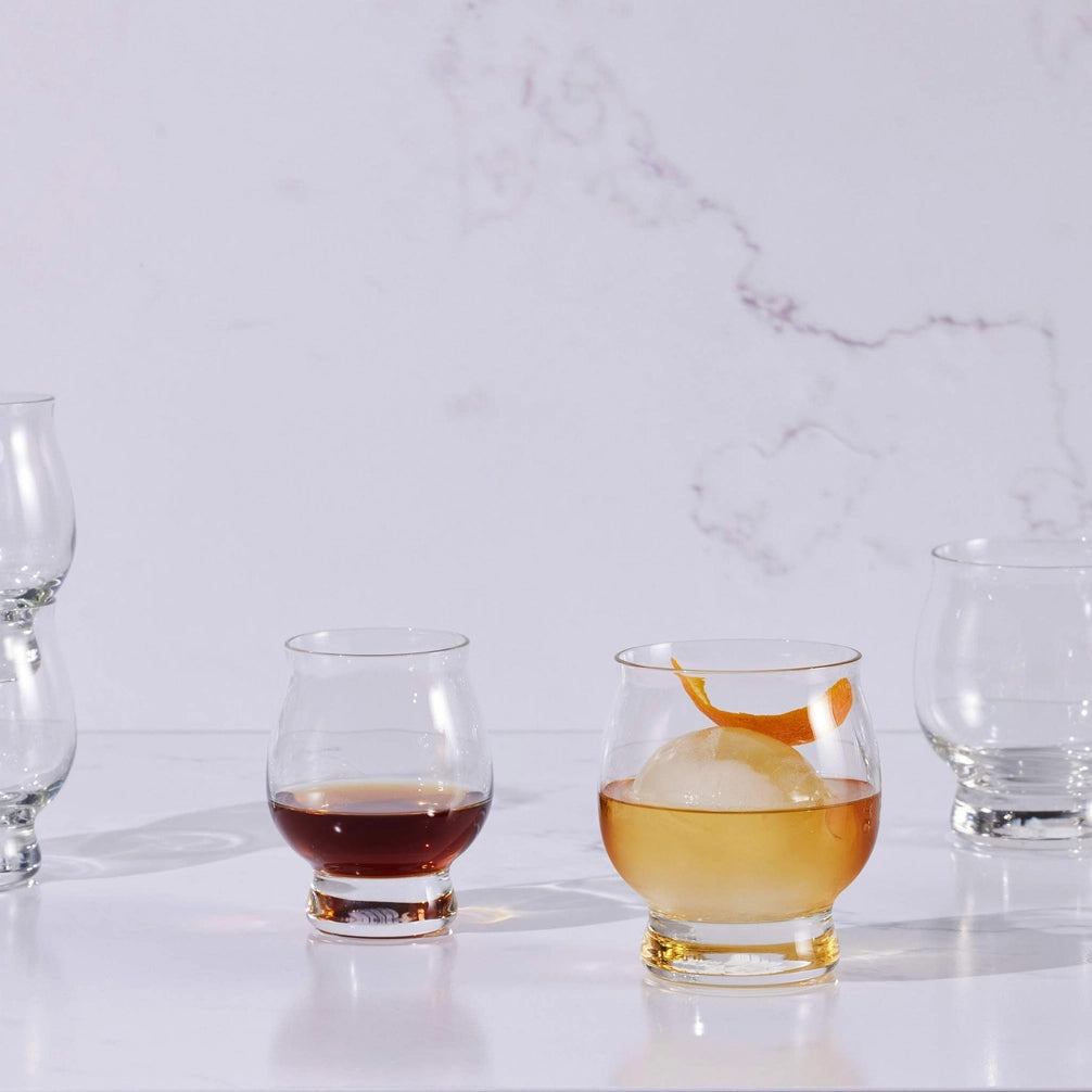 Set of modern whiskey glasses with rounded bases, shown with cocktails and neat pours, perfect for sipping in style