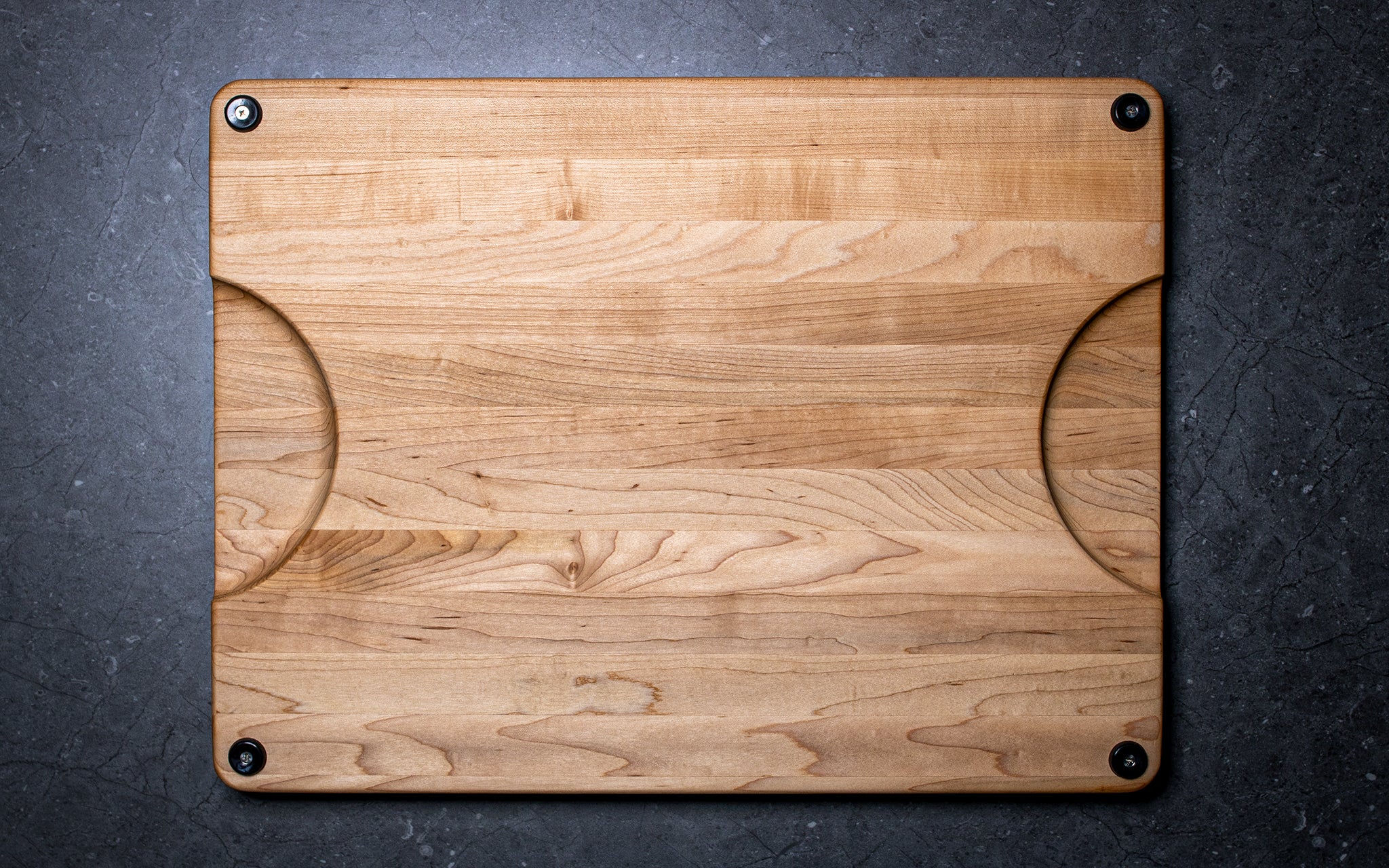 Wooden cutting board with rounded corners on a dark surface