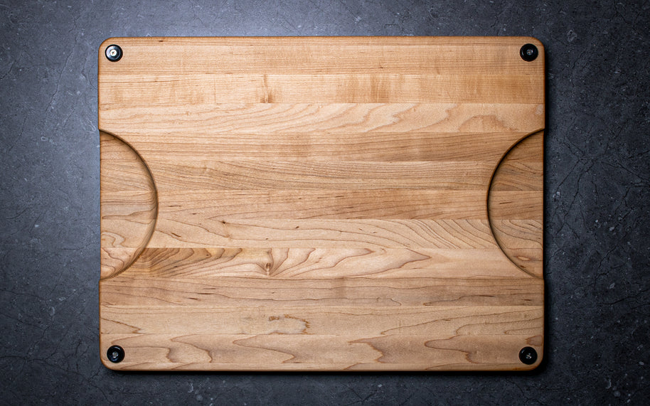 Wooden cutting board with rounded corners on a dark surface