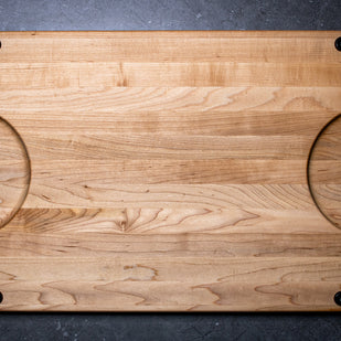 Wooden cutting board with rounded corners on a dark surface
