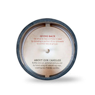 Top view of a candle with a printed message inside the container. The text reads: “GIVING BACK: We strive to help animals in need by donating a portion of our proceeds to animal rescue groups. ABOUT OUR CANDLES: Bottles are cut, polished and poured by hand using all natural soy wax, creating eco-friendly candles.”