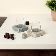 Two glasses sit in square stone bases with separate chilling rocks, blending rustic function with modern tabletop style
