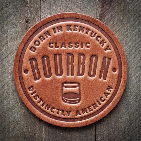 Round leather coaster embossed with the words ‘Born in Kentucky – Classic Bourbon – Distinctly American’ and a whiskey glass icon, rustic bar accessory