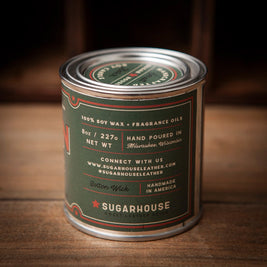 Back of Sugarhouse Cabin Fever soy candle tin. Label details: 100% soy wax + fragrance oils, 8oz / 227g, hand poured in Milwaukee, Wisconsin, cotton wick, handmade in America. Sugarhouse branding and website included
