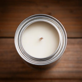 Top view of an unused soy candle in a silver tin container, showing a centered cotton wick surrounded by smooth, creamy white wax.