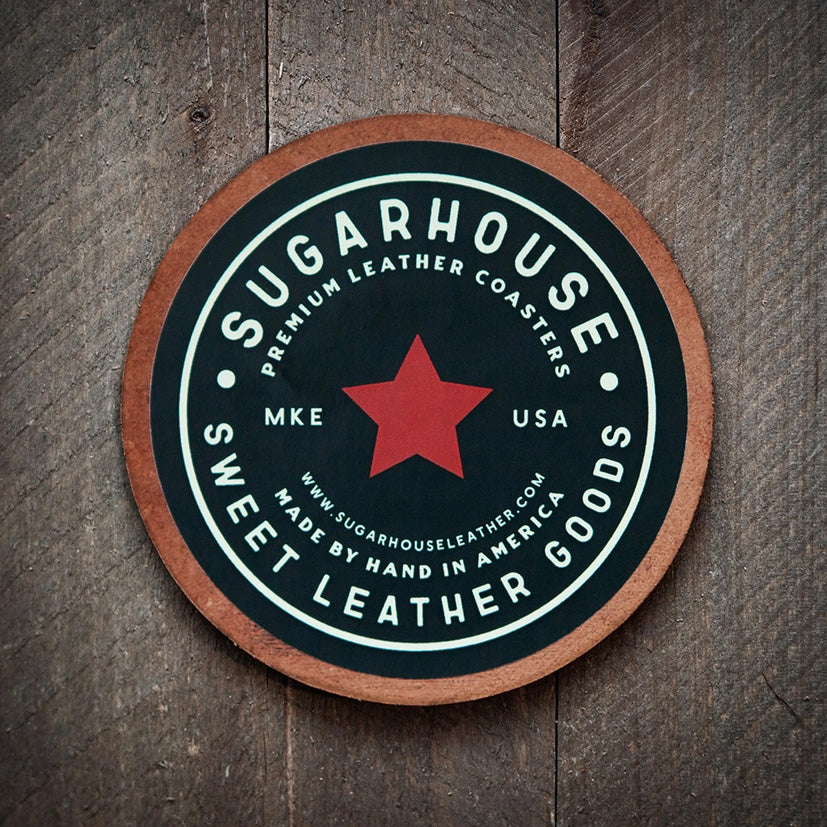 Round leather coaster with a black face and bold red star in the center. White text around the star reads: ‘Sugarhouse Premium Leather Coasters, Sweet Leather Goods, Made by Hand in America, MKE USA