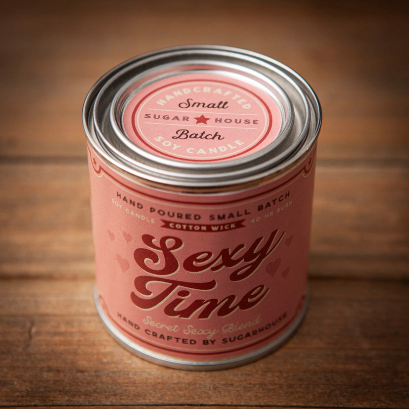 Pink Sugarhouse soy candle labeled “Sexy Time – Secret Sexy Blend,” in a tin can with a vintage-style design and metal lid, placed on a wooden surface
