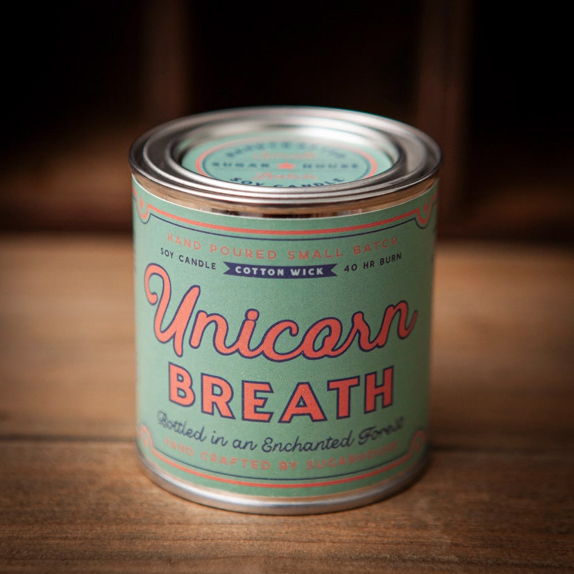 Unicorn Breath soy candle tin with pastel mint green label and pink retro script. Text reads: Unicorn Breath – Bottled in an Enchanted Forest. Hand-poured small batch soy candle with cotton wick, 40-hour burn